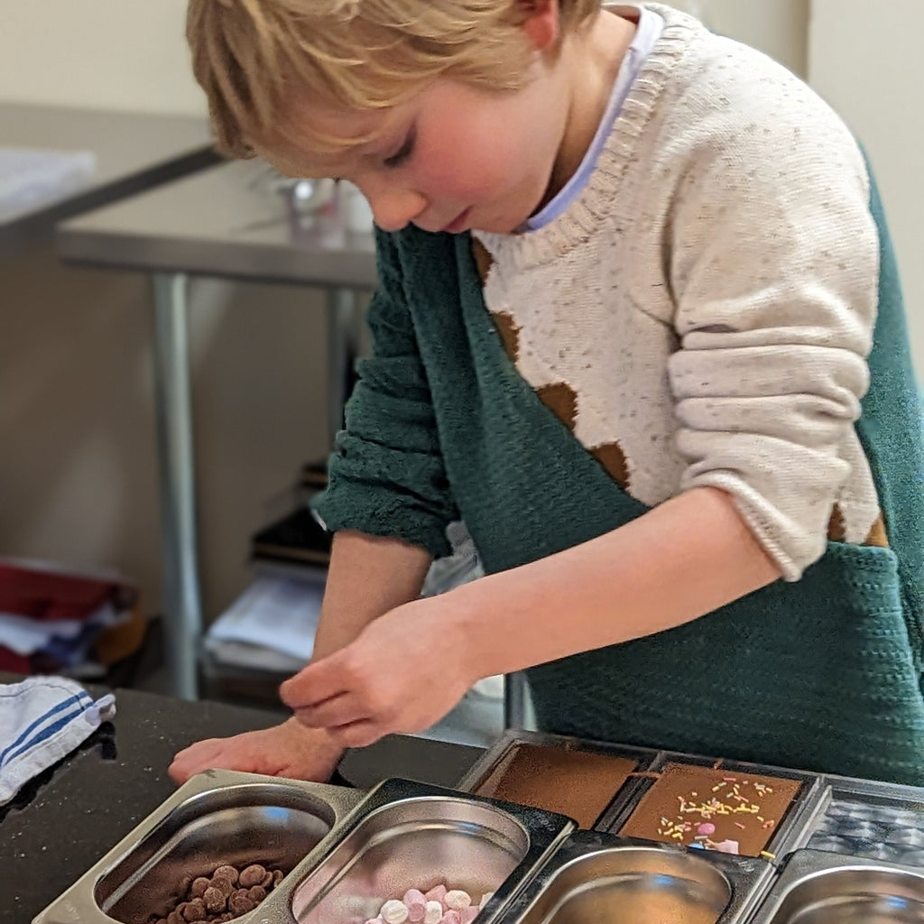 Child in a kitchen setting making chocolate bars